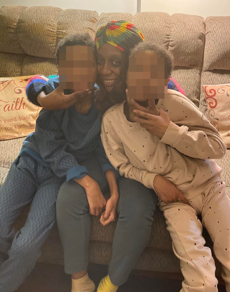 Geneva Jarvis smiling while hugging Adonis Jarvis and his twin brother, their faces blurred.
