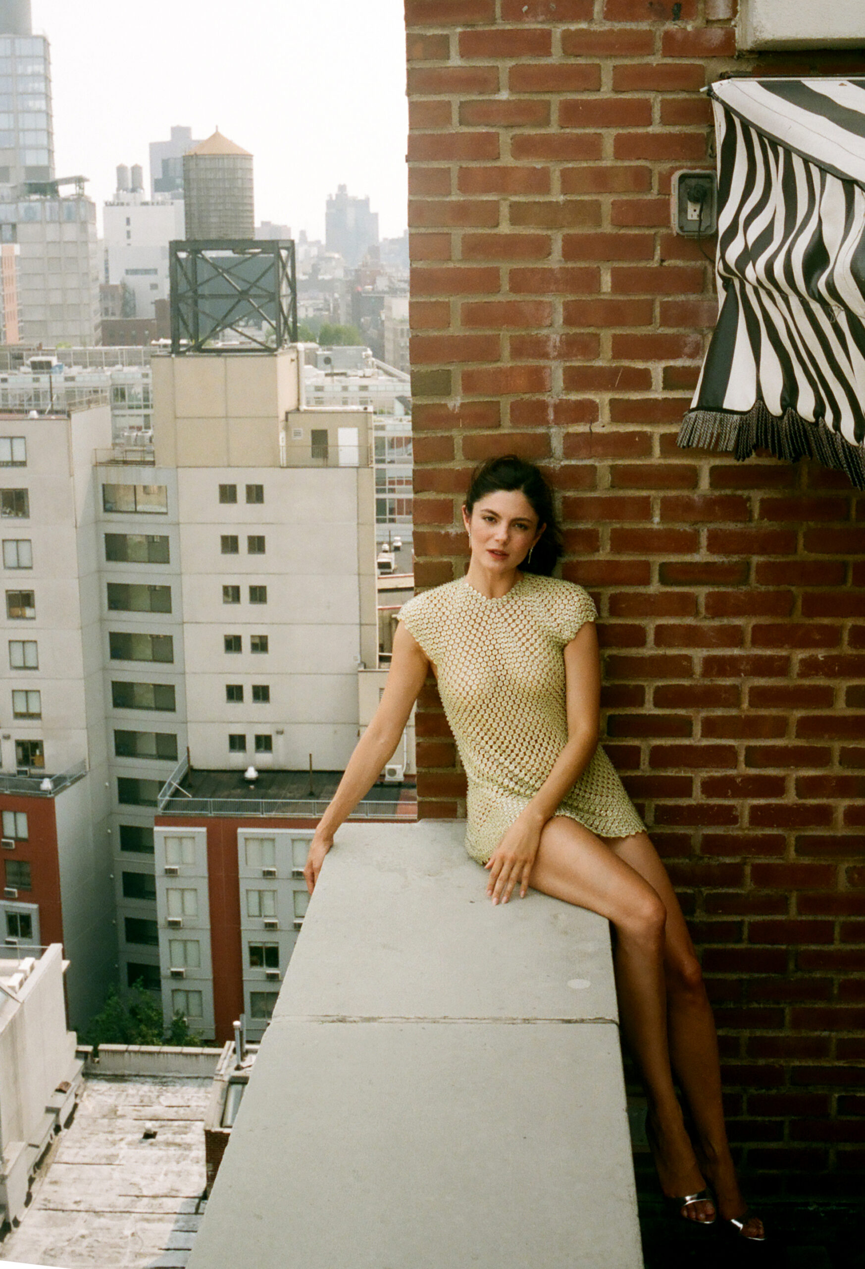 Monica Barbaro sitting on the edge of a balcony