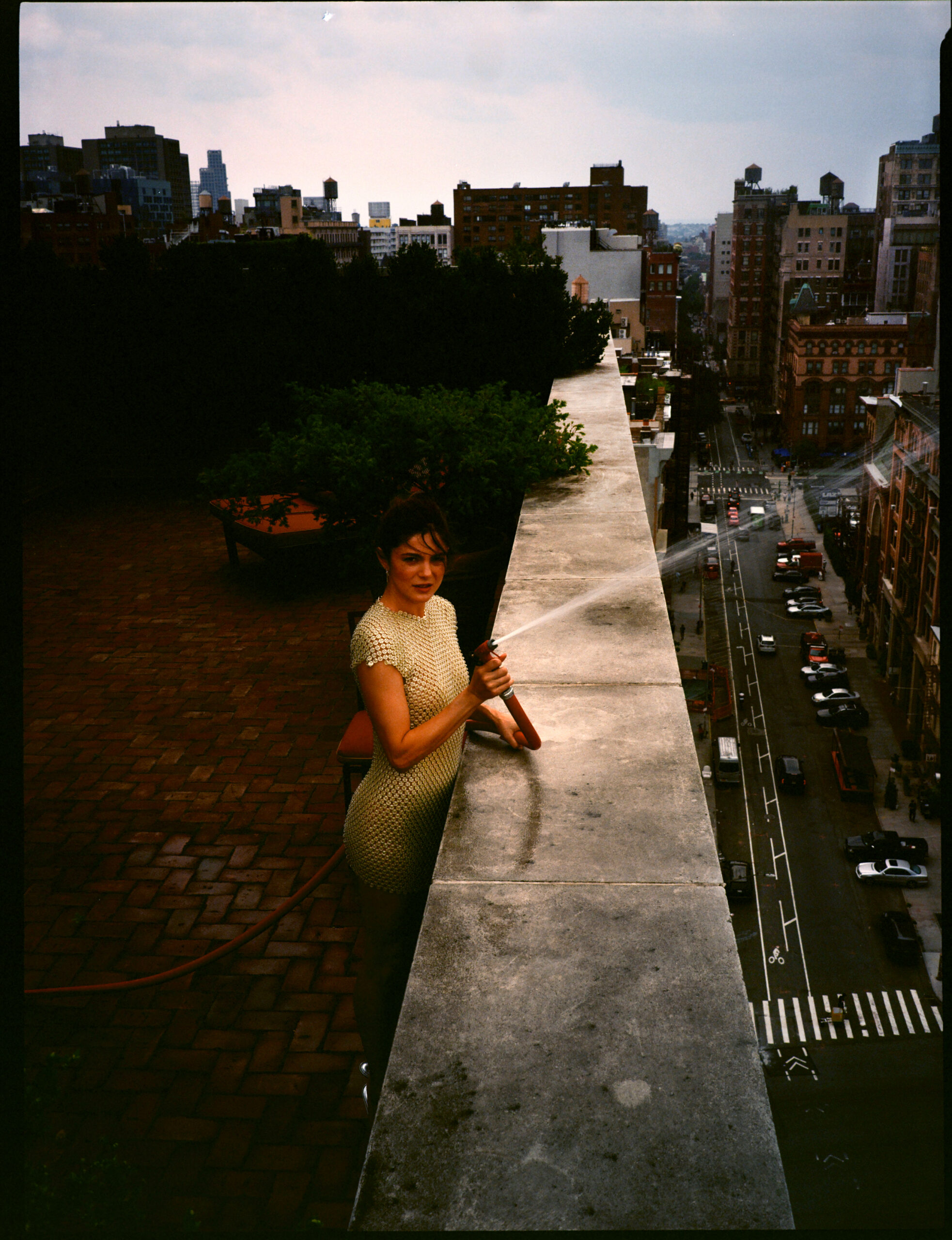 Monica Barbaro spraying a house from the roof of a building