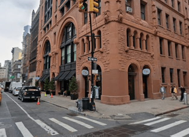 Corner view of 484-490 Broome St. in Soho, a Romanesque Revival red-brick structure featuring broad arches and ornate terra-cotta details.