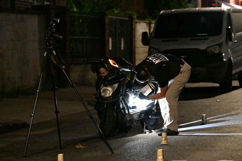NYPD officers investigate the scene of a fatal shooting near 899 Crescent Street in Brooklyn, New York.