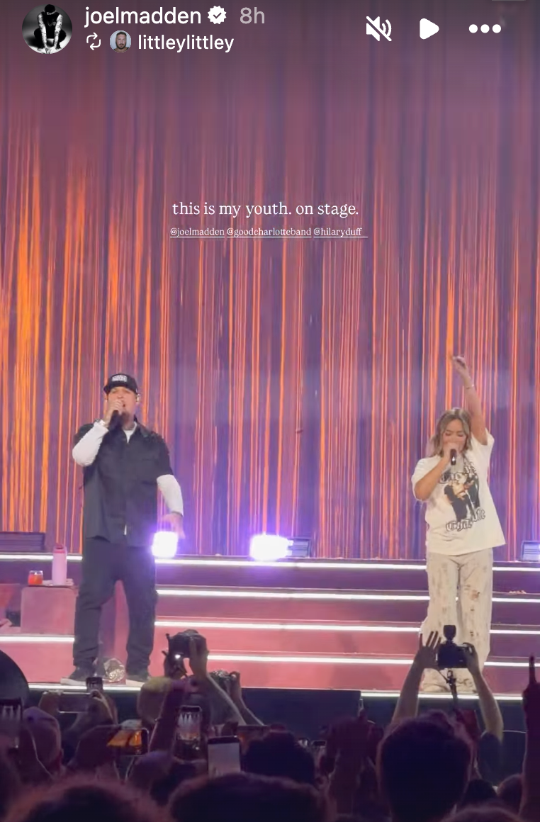 Two performers on stage with vibrant lighting, engaging with a cheering crowd during a live concert. Two performers on stage with vibrant lighting, engaging with a cheering crowd during a live concert.