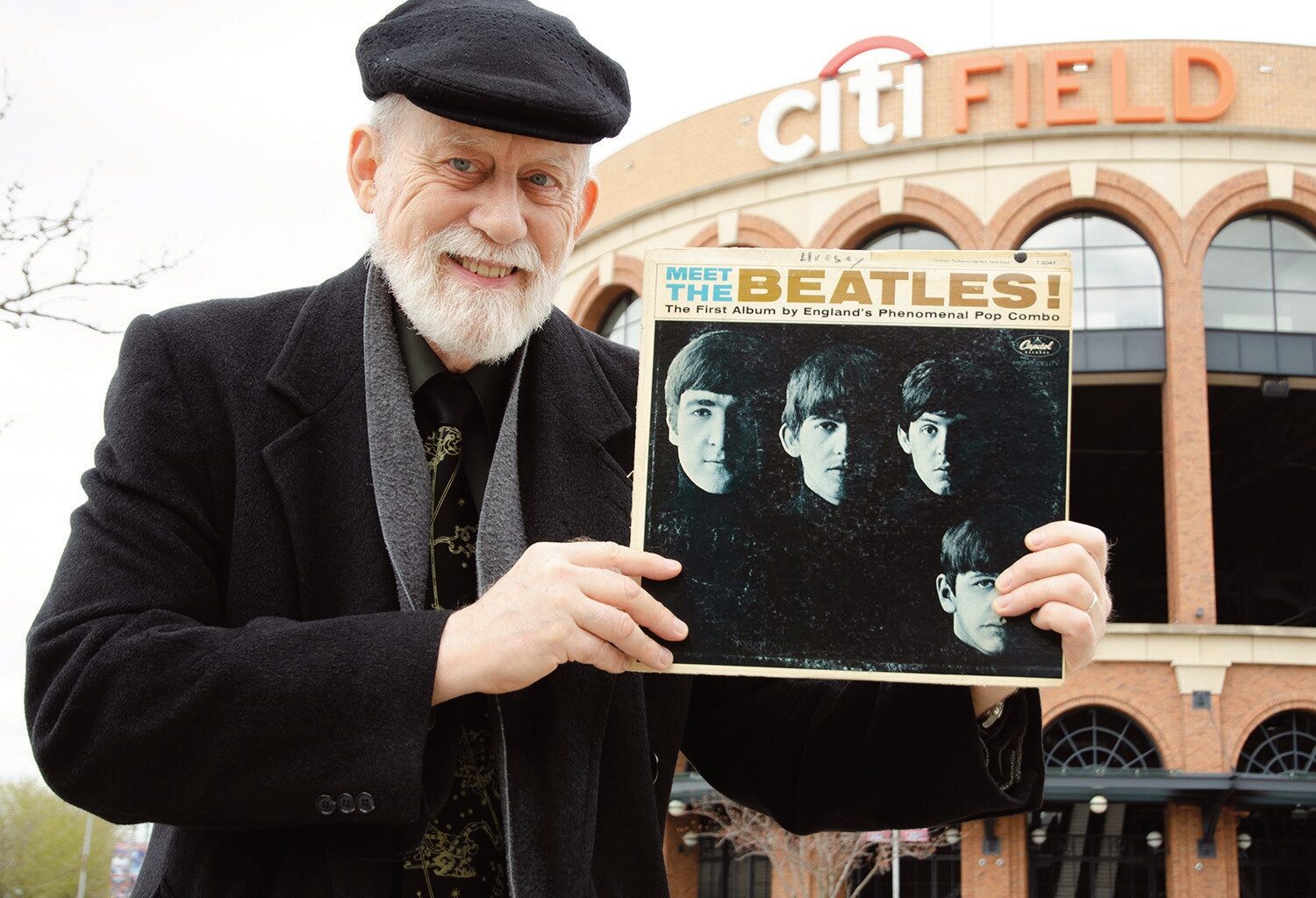 Dennis Livesey holds his vintage “Meet The Beat­les!” album cover at the former location of Shea Stadium, currently the parking lot of Citi Field. Photo: David Paone