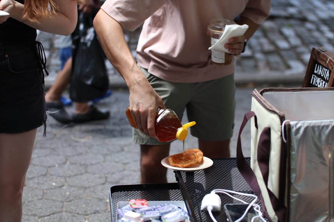 Someone squeezing honey onto a piece of crispy bread.