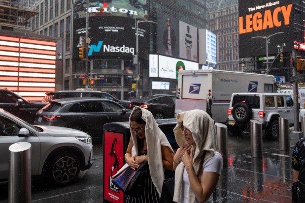 People cover themselves from the rain as they walk past the Nasdaq MarketSite, Thursday, Aug. 6, 2026, in New York. 