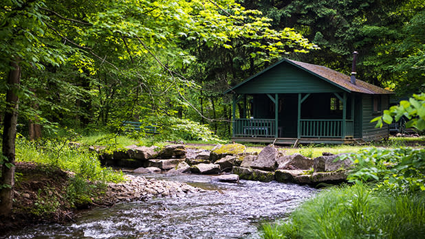 A green cabin along a stream in Allegany State Park
