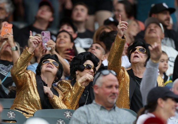 Fans dressed like Elvis Presley look to the sky as a parachute team descends to the field before a White Sox-Mets game Friday, Aug. 21, 2026, at Rate Field. (Chris Sweda/Chicago Tribune)
