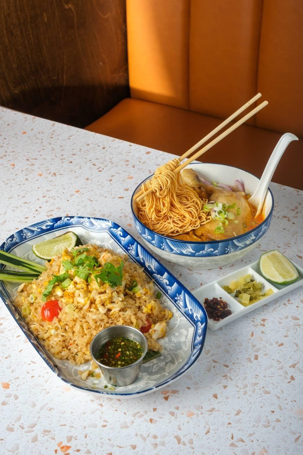 A bowl of noodle soup next to a plate of rice.