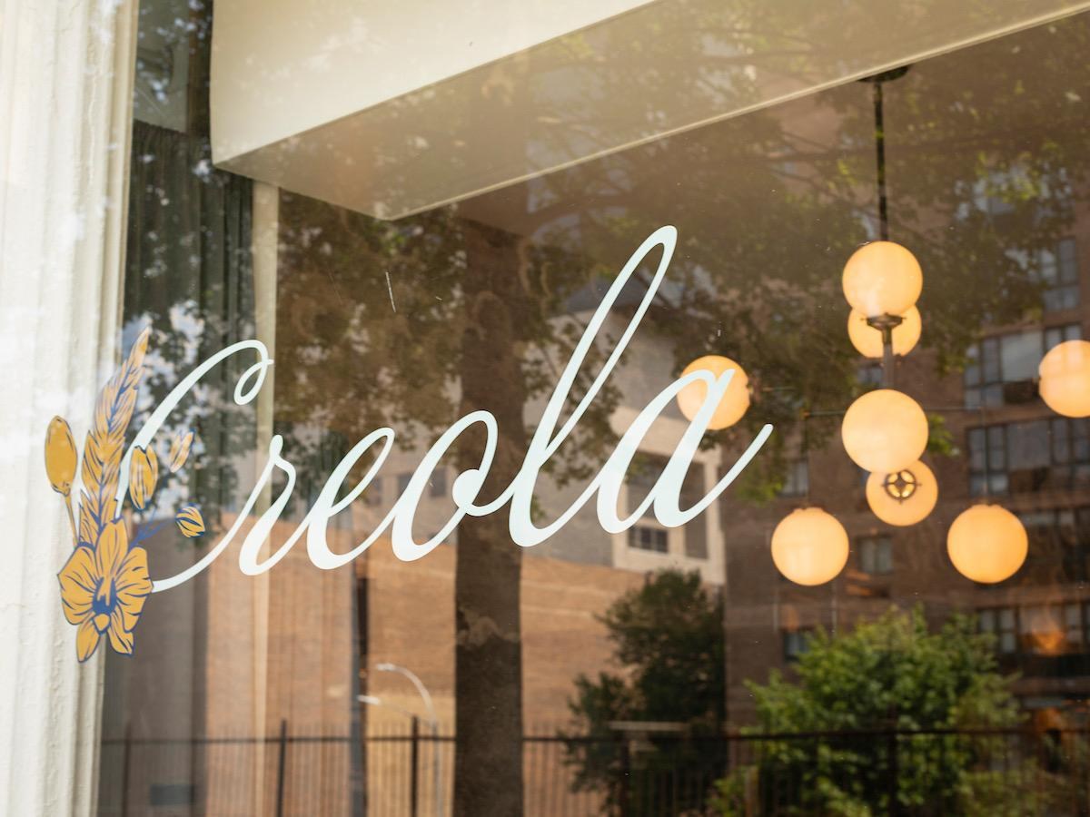 A restaurant window with the word Creola on it.