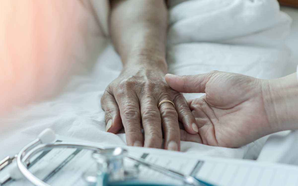 nurse holding patient hand in hospice care