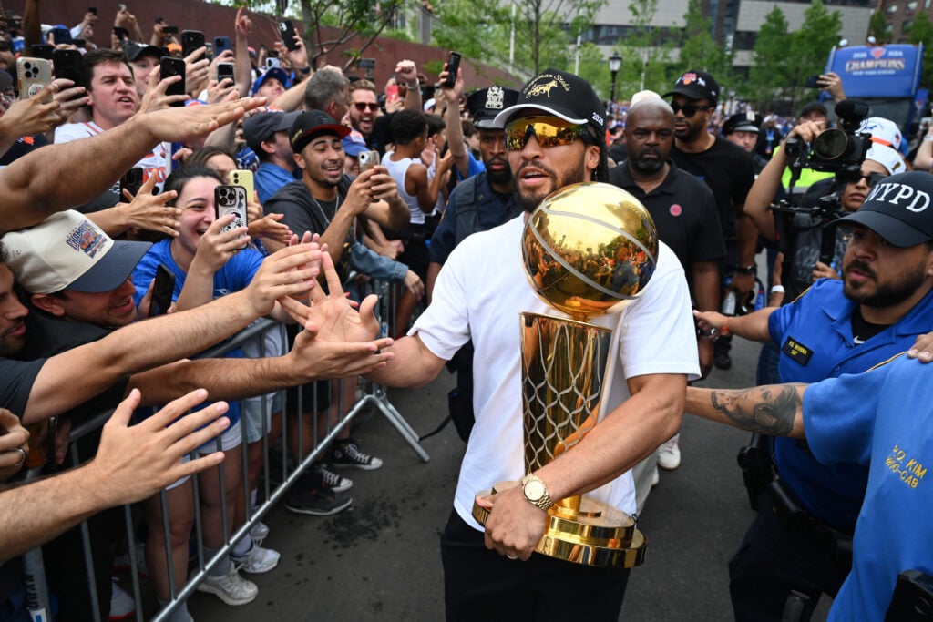Jalen Brunson of the New York Knicks holds the trophy during the New York Knicks Championship ticker tape parade and victory rally celebrating winning the 2026 NBA Finals on June 18, 2026 in New York City. The New York Knicks defeated the San Antonio Spurs in five games to win their first NBA Championship in 53 years.