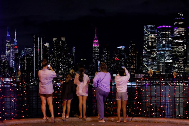 People watch the Empire State Building lit up in pink to honor the late singer-songwriter Dolly Parton in New York on Aug. 25, 2026. (Photo by Leonardo MUNOZ / AFP via Getty Images)