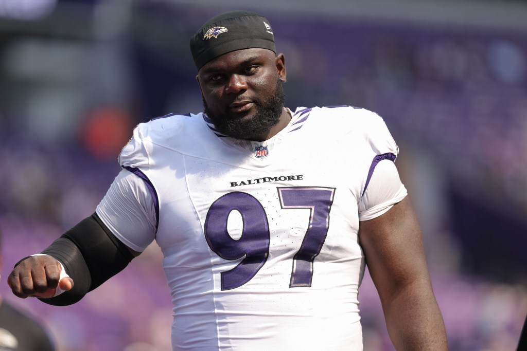 A Baltimore Ravens player in a white and purple jersey with the number 97.