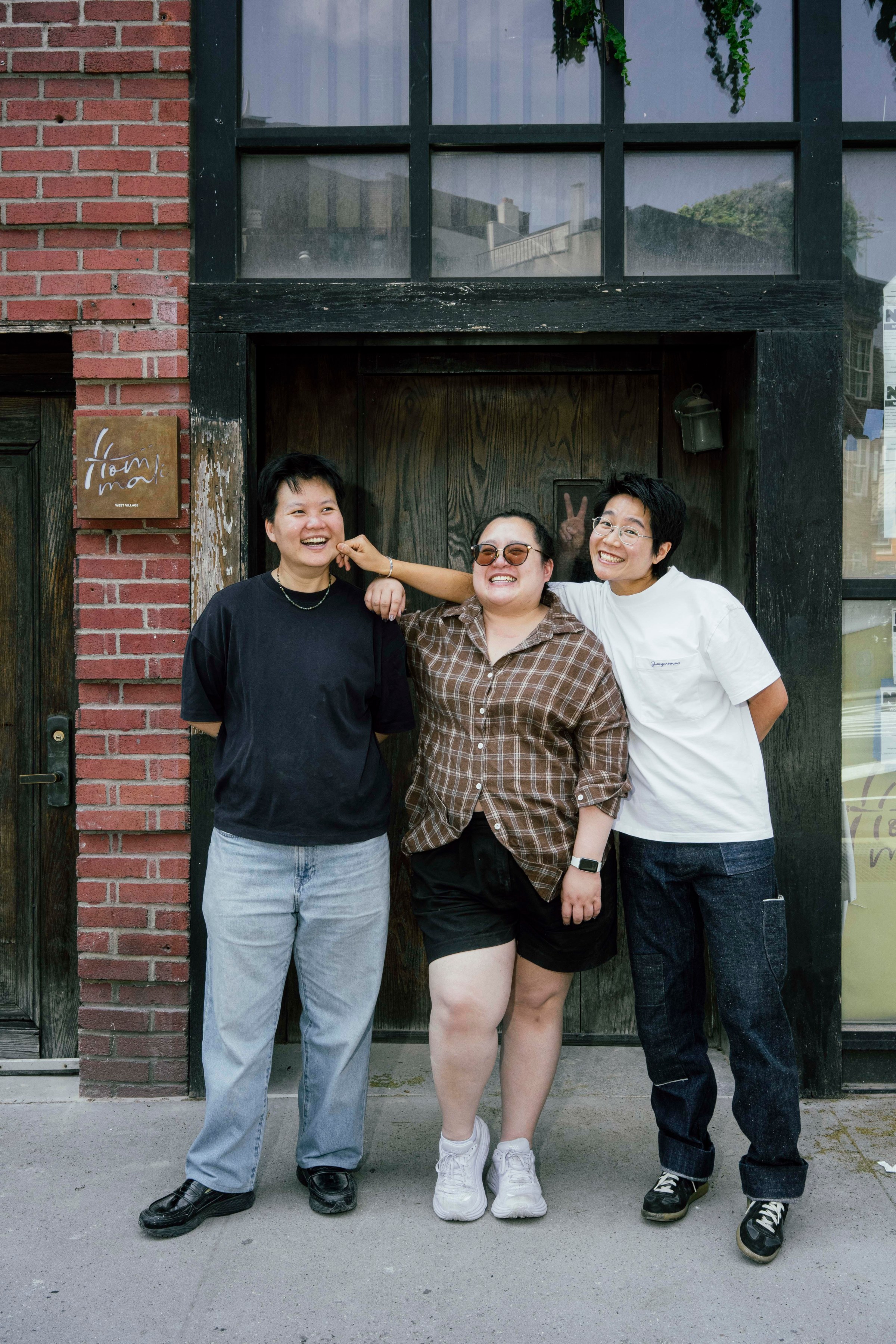 Three people standing in front of a restaurant.