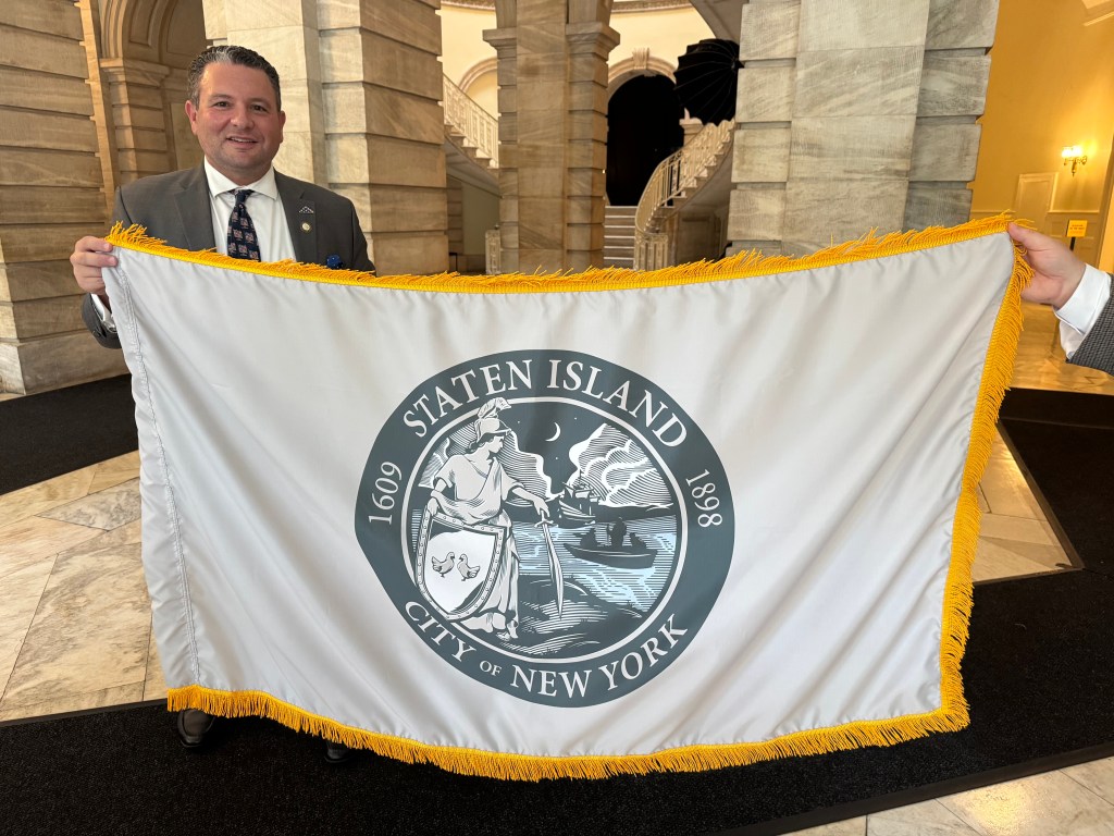 Staten Island City Councilmember Frank Marano poses with his borough's flag. 