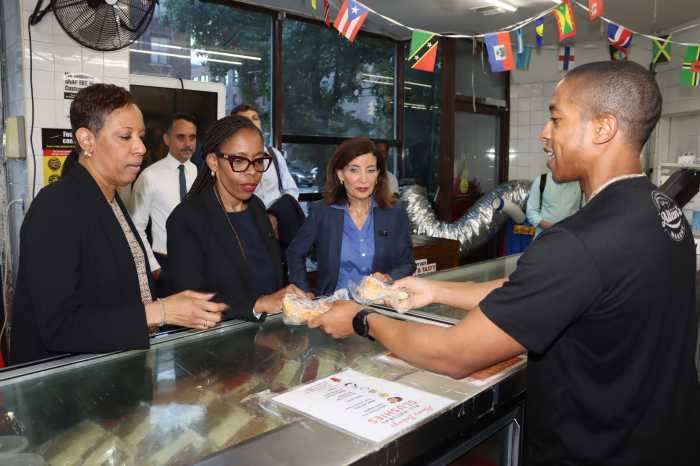 Christian Smith, director of Business Development at Allan's Bakery, sells Caribbean pastry to Gov. Kathy Hochul, right, former City Council Speaker Adrienne Adams, left, and City Council Rita Joseph.