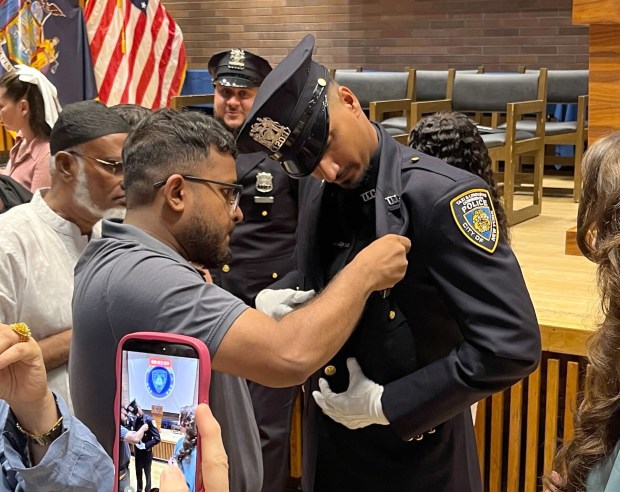 Family members pin a shield on Ofc. Ashik Chowdhury at the ceremony on Tuesday.