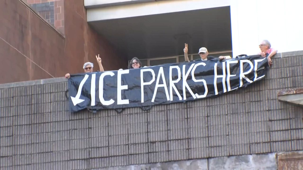 Protesters holding a sign that reads "ICE parks here"
