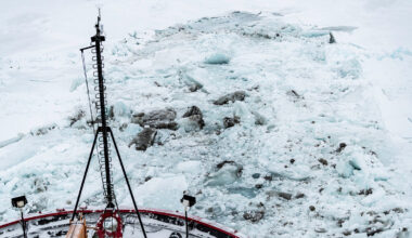 Icebreaker ships nose as it breaks through thick layer of ice