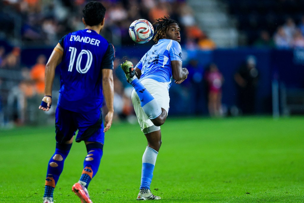 A New York City FC player jumping to head the ball during a game against FC Cincinnati.