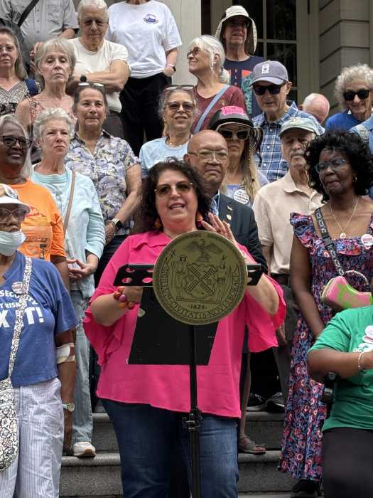 woman in pink shirt talking as a group stands behind her