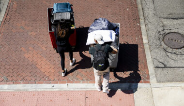 Aerial view of two students pushing luggage carts across a brick courtyard on move-in day.