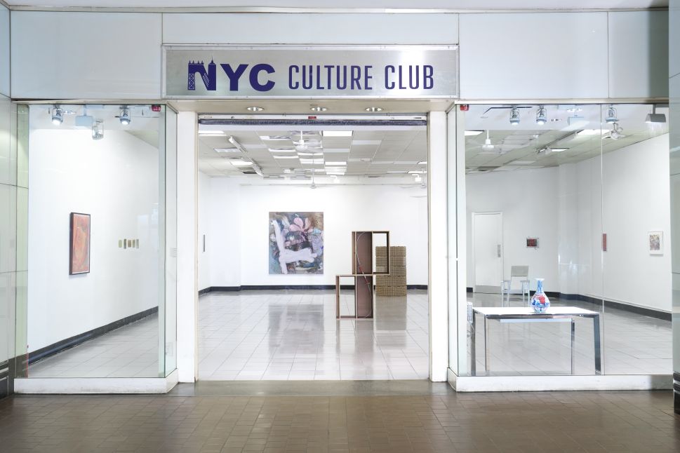 The NYC Culture Club entrance opens into a white gallery space with artworks visible on the walls and floor from the transit corridor outside.