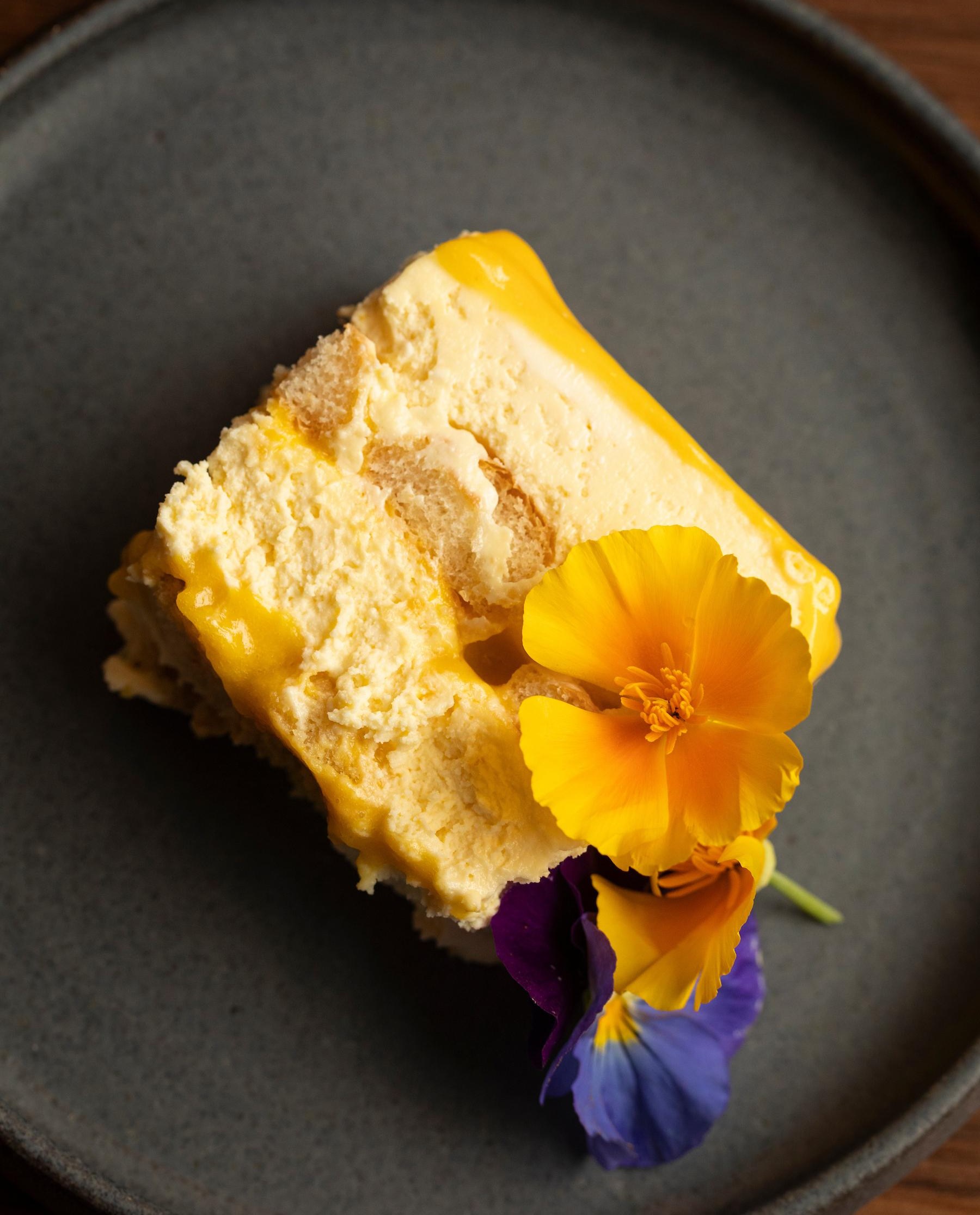 A yellow cream dessert with a flower on it.