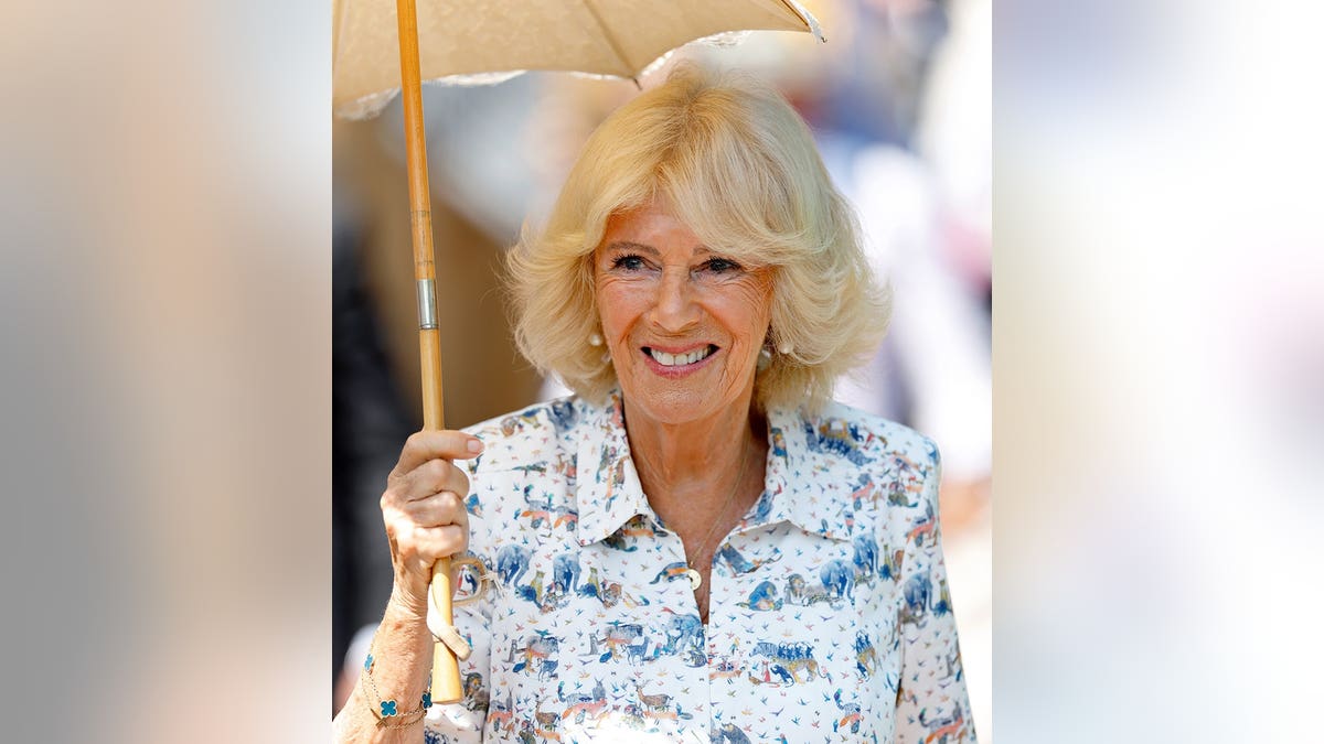 Queen Camilla shelters under a parasol at London Zoo.