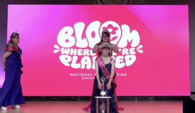 girl in a blue dress with a sash and trophy, with another woman putting a crown on her head.
