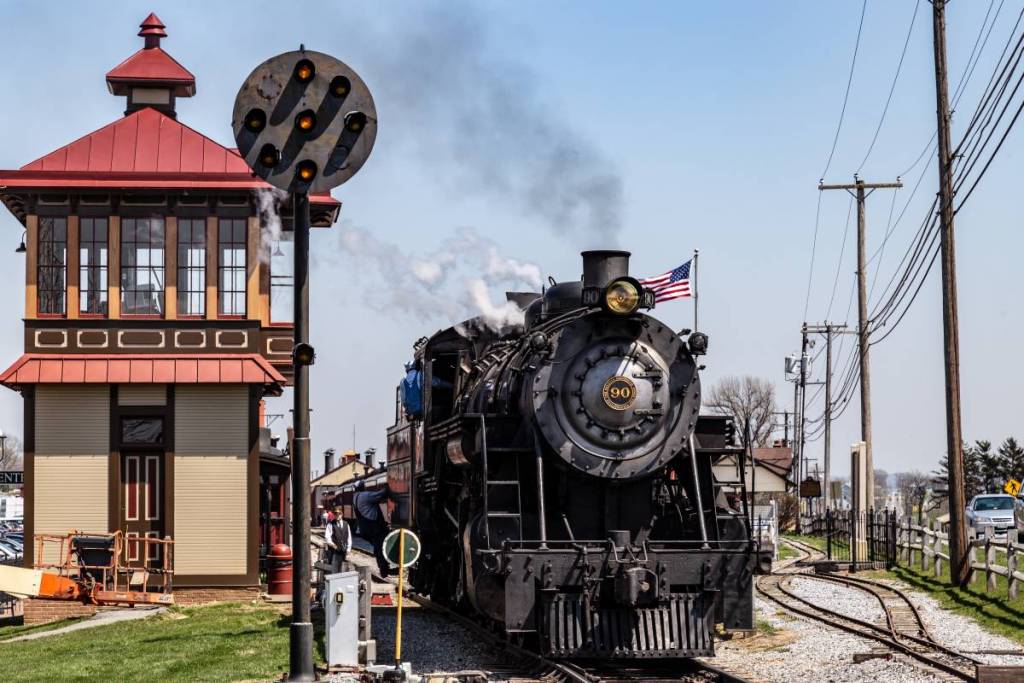 Strasburg, PA, USA - April 14, 2018 A smokey steam locomotive operated by the Strasburg Rail Road stops at the train station in Lancaster County, PA