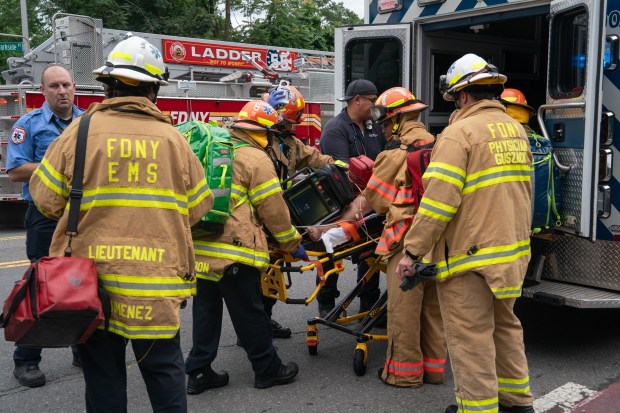 FDNY firefighters and EMTs rush a fire victim to an ambulance during a massive Bronx fire in a five-story apartment building on E. 209th St. near Parkside Place in the Bronx on Wednesday, Aug. 5, 2026.. (Barry Williams/ New York Daily News)