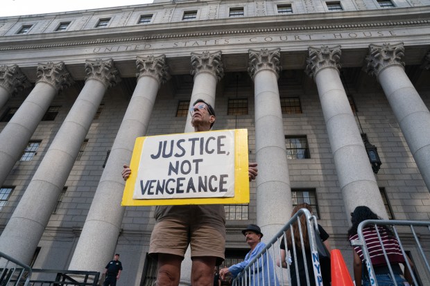 A man holds a sign outside of Manhattan Federal Court on the day of a hearing for Luigi Mangione on Friday, Aug. 14, 2026, in New York. (Barry Williams / New York Daily News)