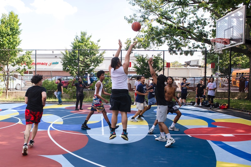 Young men play basketball on a brightly-painted court.