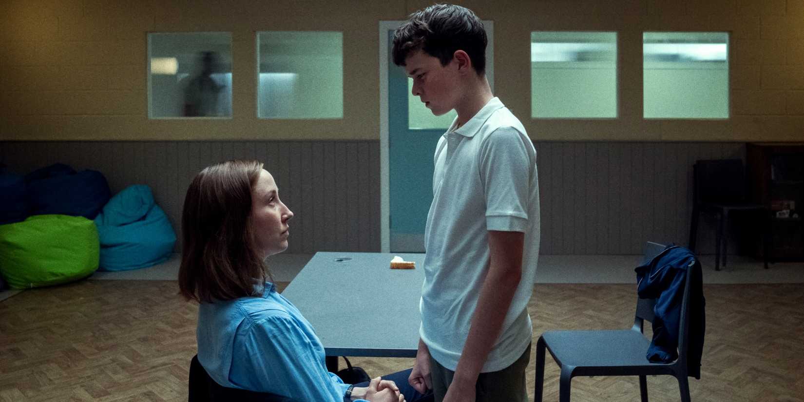 Owen Cooper as Jamie Miller standing over Erin Doherty as Briony Ariston as she sits in Adolescence
