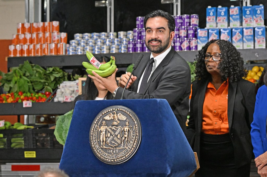 Mayor Mamdani announcing an RFP to get bids on a private business to help manage city-run supermarkets, holding up plantains with a 30% discount sticker.