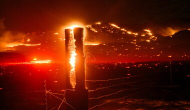 Seen in a long exposure, flames consume a fencepost as the Bug Fire burns near Doyle in unincorporated Lassen County, Calif., on Thursday, Aug. 13, 2026. (AP Photo/Noah Berger)