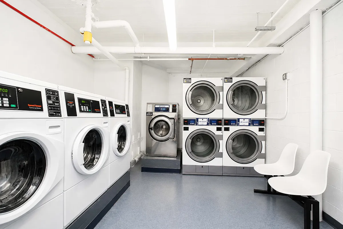 laundry room with multiple washers and dryers and seating
