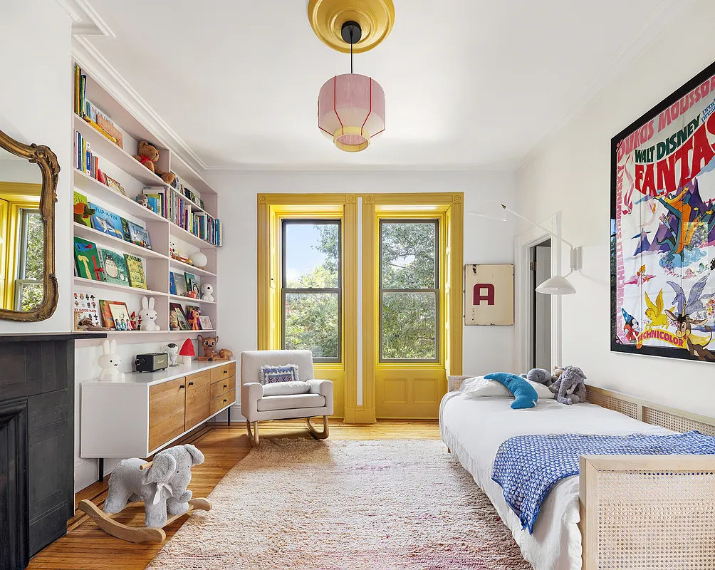 bedrom with window trim painted yellow, a stone mantel and wood floor