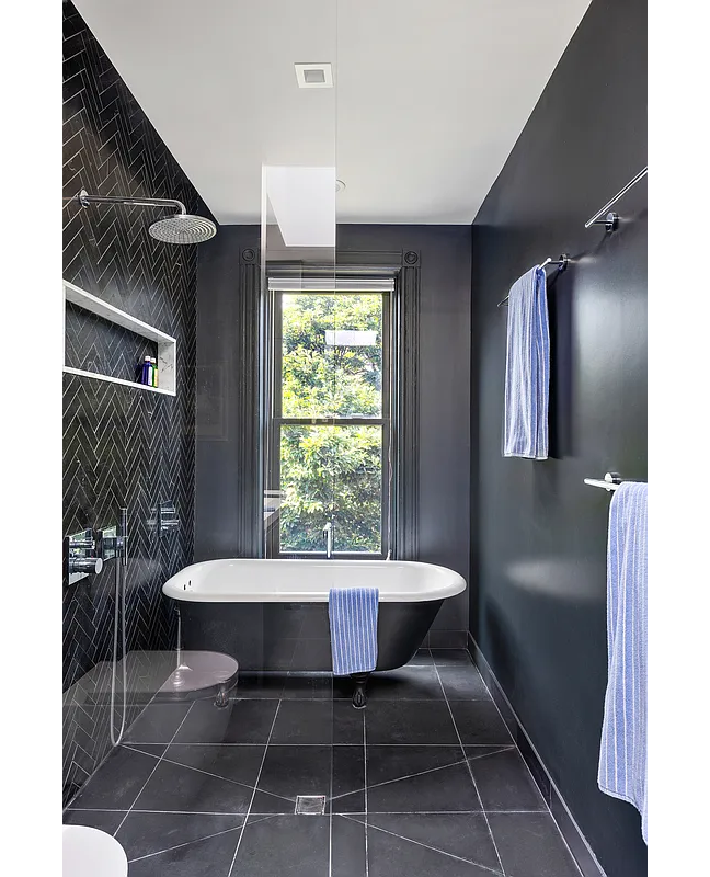 bathroom with black floor and wall tile, claw foot tub