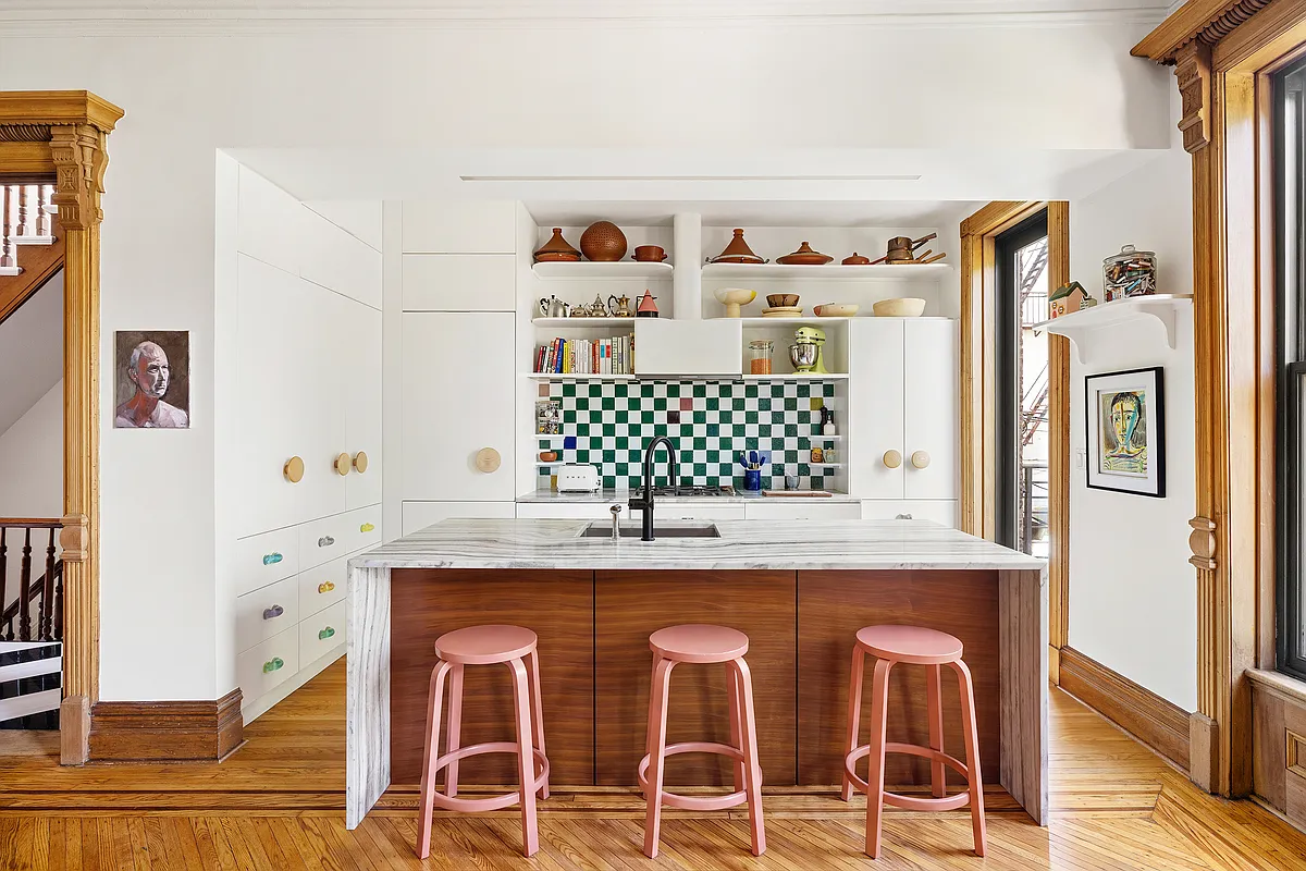 kitchen with white cabinets, large marble and wood island with coral stools