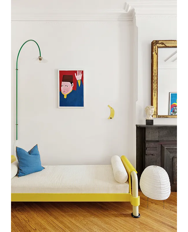 parlor with a yellow daybed next to a stone mantel