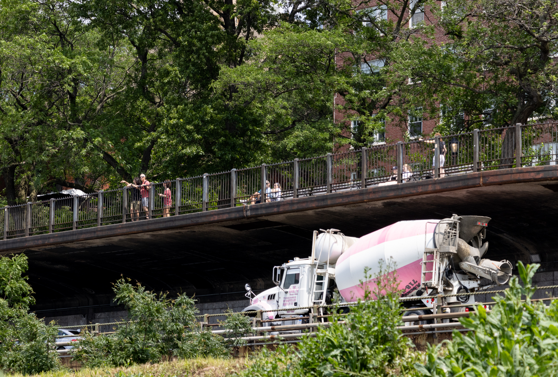 a cement truck on the bqe with people on the brooklyn heights promenade above