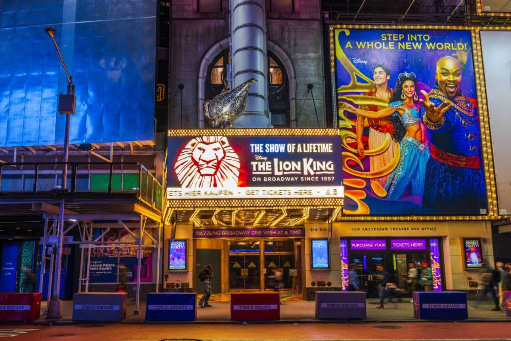 View of Times Square in Manhattan with Music Theater hosting The Lion King musical and illuminated advertising billboards. New York