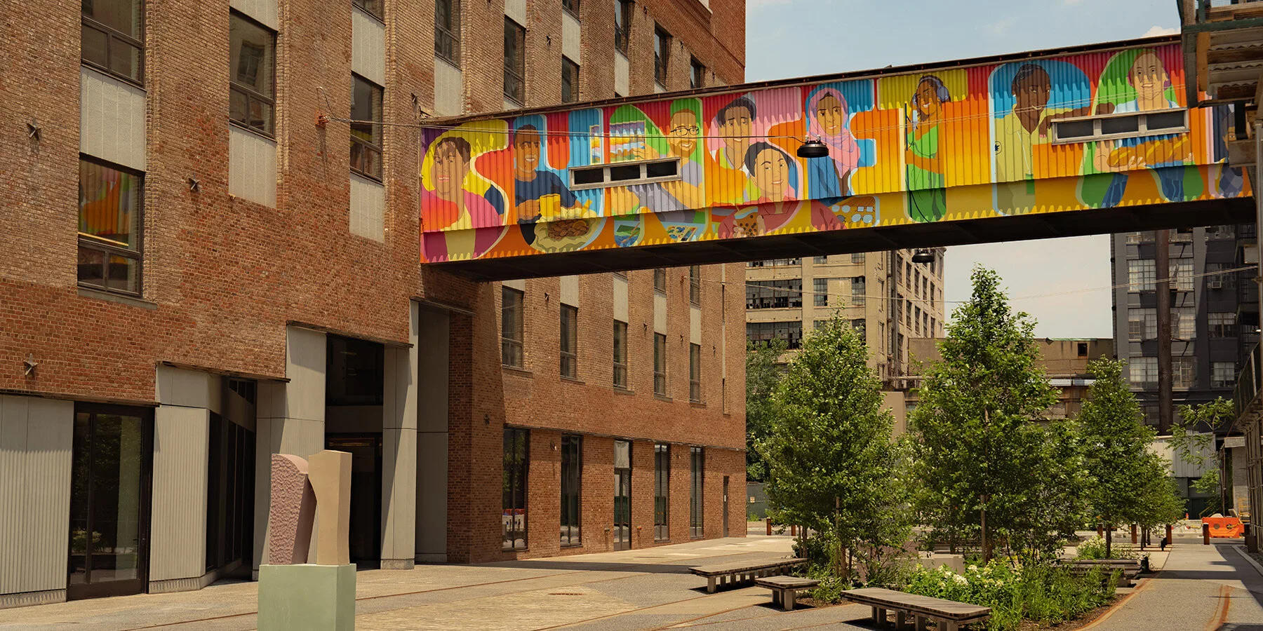 Brooklyn's Sunset Park Reimagines Historic Waterfront with Vibrant Creative Community People walking along waterfront promenade with industrial buildings in background.