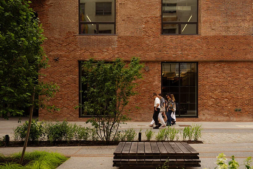Brooklyn's Sunset Park Reimagines Historic Waterfront with Vibrant Creative Community Artists collaborating at a communal table inside a renovated warehouse building.