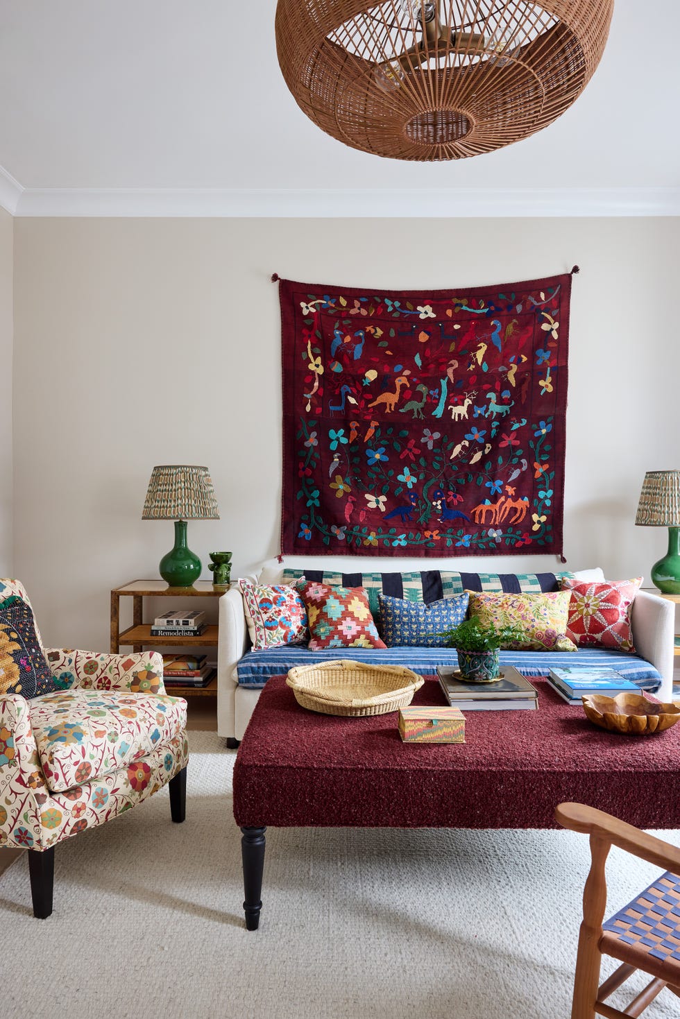 Living room with a colorful tapestry, patterned sofas, decorative pillows, and a wooden coffee table.