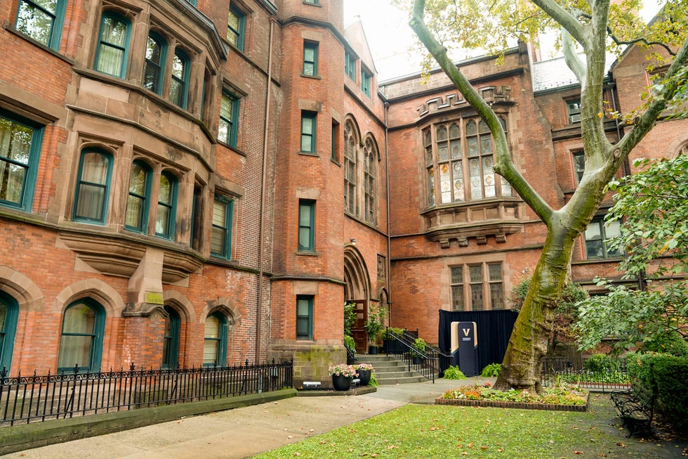 Historic brick building courtyard with green trees and a decorative entrance.