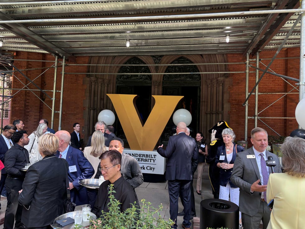 A networking event with attendees in formal attire and a large yellow "Vanderbilt University" sign in New York City.