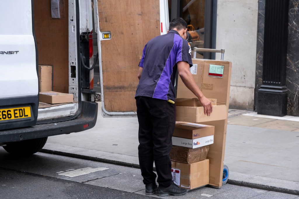 A FedEx delivery man sorts packages from the back of his van in London.